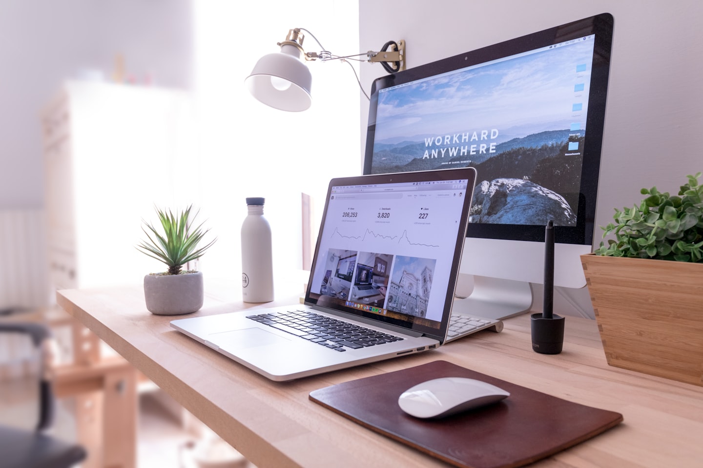 Laptop and desktop monitor on a modern wooden desk.
